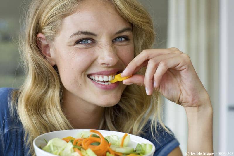 Junge blonde Frau nascht von einem Salat in wohnlicher Atmosph‰re